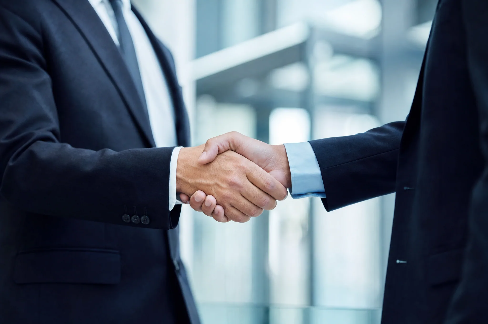 Two business professionals in suits shaking hands to close a deal.